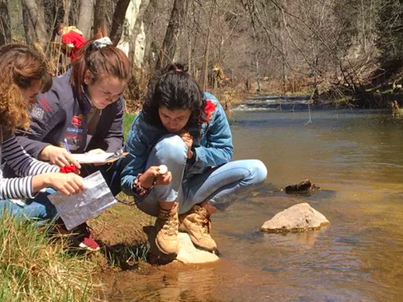 Student teams examining water by river