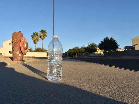 photo of a plastic water bottle on a street near a fire hydrant