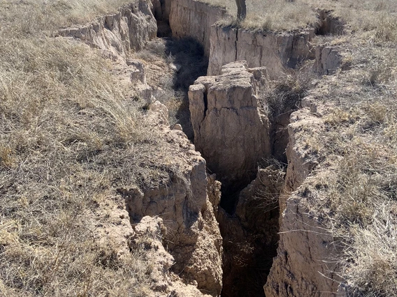 a photo of a man standing near a very large fissure. 30-40 feet long and quite deep