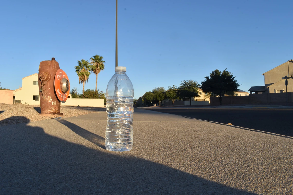photo of a plastic water bottle on a street near a fire hydrant