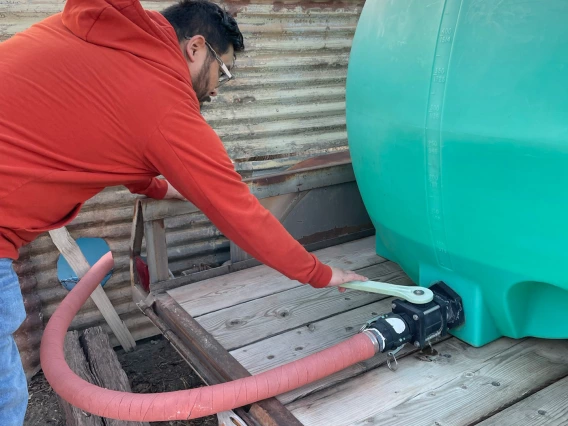 person adjusting hose on tank