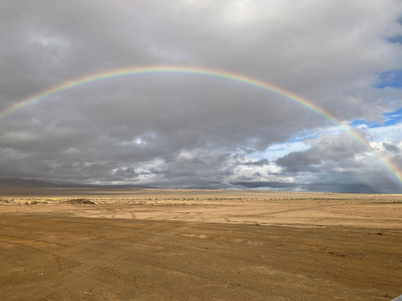 Trevor Pontifex photo showing a rainbow arc over a desert expanse with clouds in the background