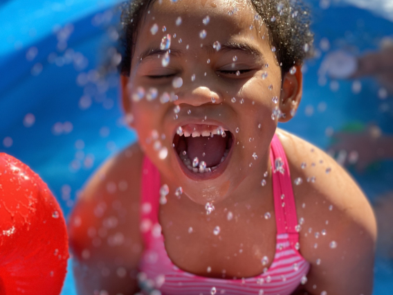 Jael Walker photo showing a child playing in water and laughing with water splashing all around her