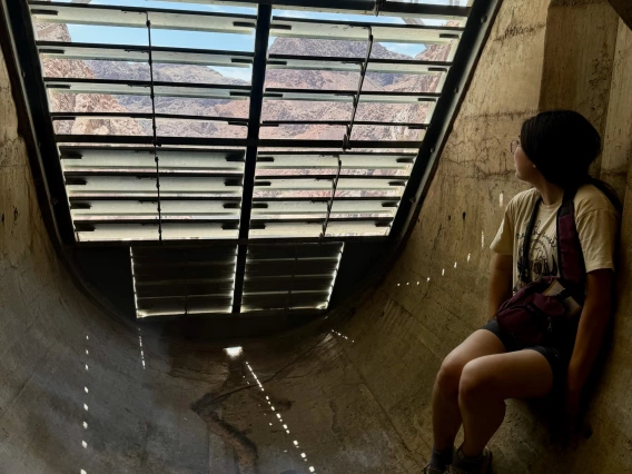 a photo of a person looking through a grate while sitting inside hoover dam