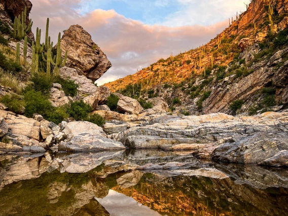 photo showing a pool in a desert setting with a reflection. clouds and blue sky.