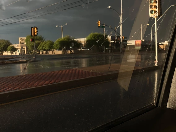 photo taken through car windshield show a city street and stormy weather