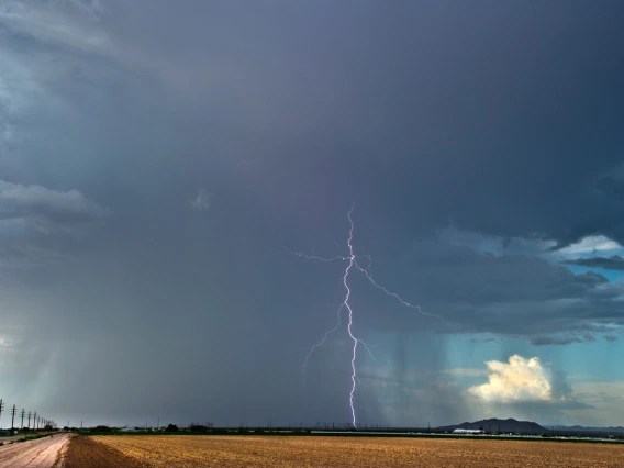 an agricultural landscape showing rain and a single lightning bolt