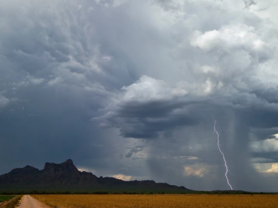 landscape showing rain and a single lightning bolt