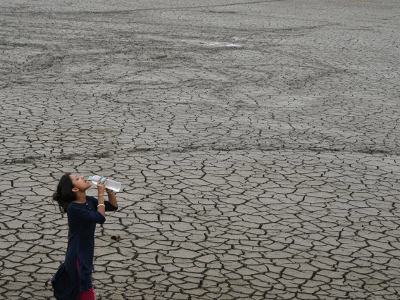 photo of a person drinking water on cracked earth landscape