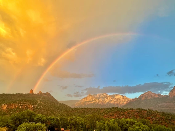 photo showing a double rainbow in an arizona landscape. blue sky with orange clouds