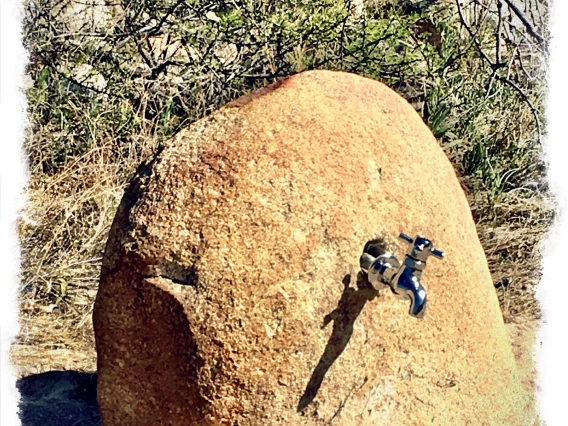 photo of a desert rock with a water spigot coming out of it