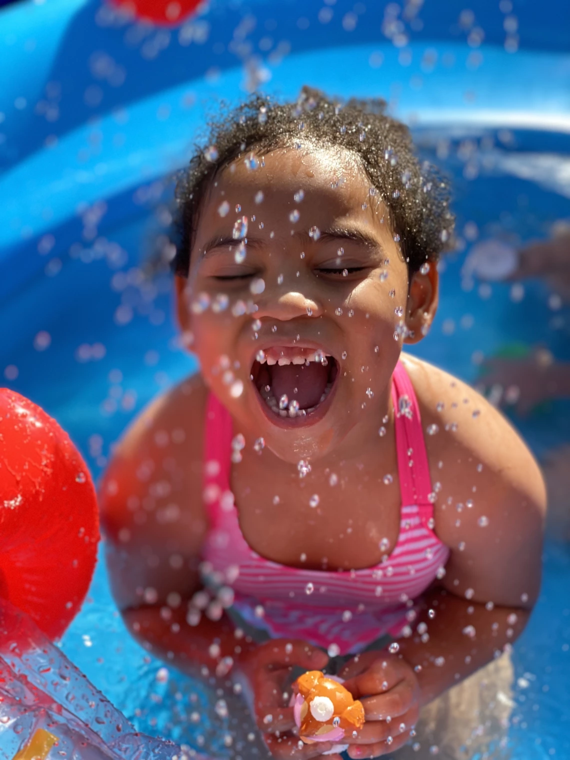 Jael Walker photo showing a child playing in water and laughing with water splashing all around her