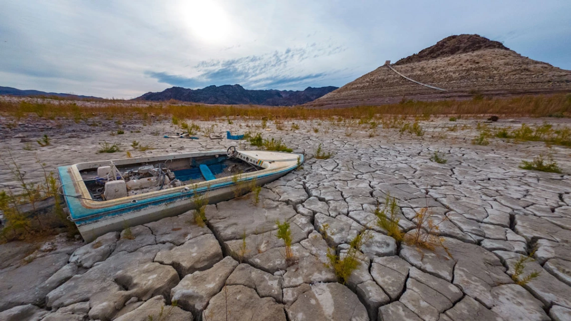 photo showing lake mead with boat on cracked earth