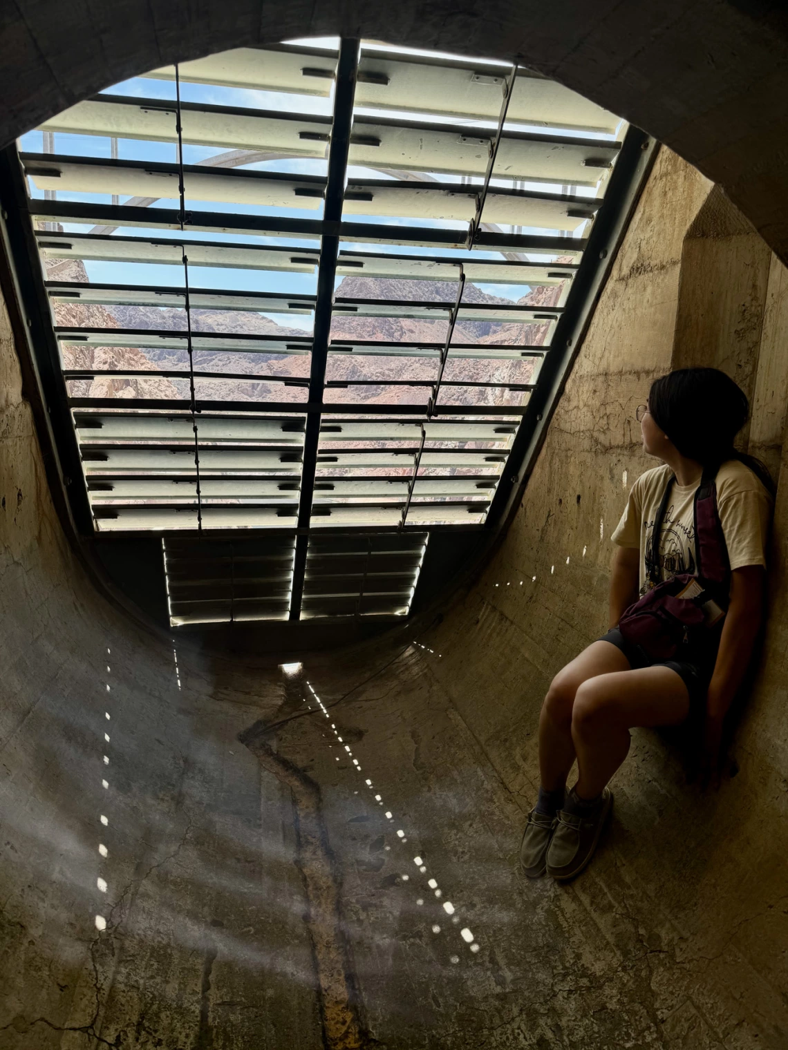 a photo of a person looking through a grate while sitting inside hoover dam