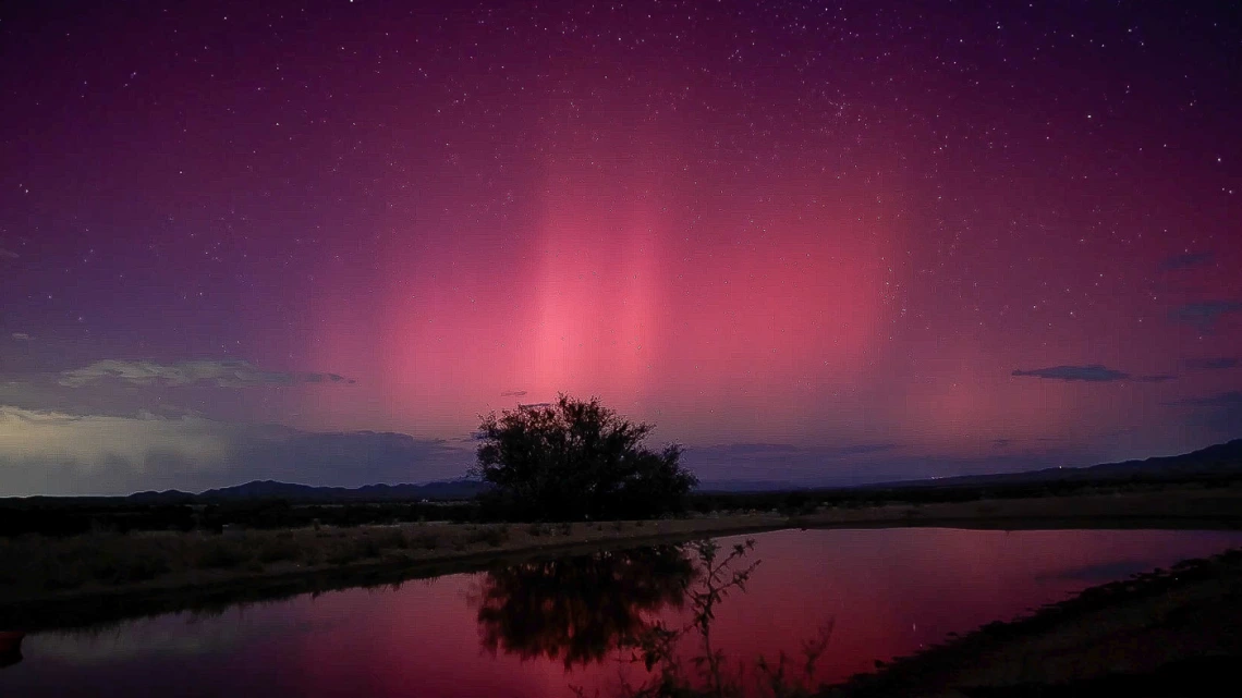 photo showing Las Cienegas National Conservation Area at night. Aurora Borealis can be seen in the sky. Reds and purples define the sky