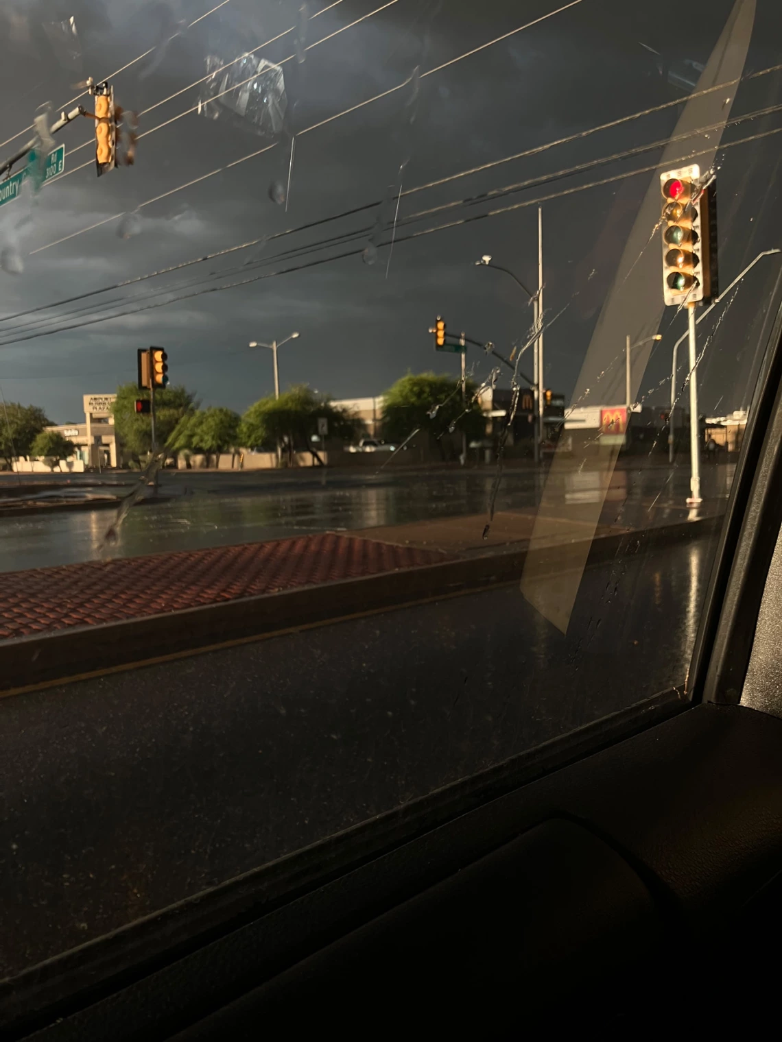 photo taken through car windshield show a city street and stormy weather