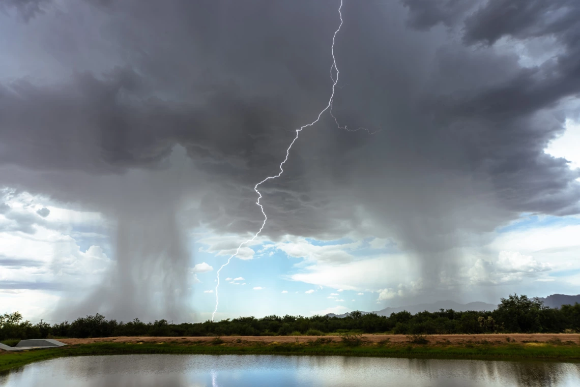 a body of water with rainclouds and lightning