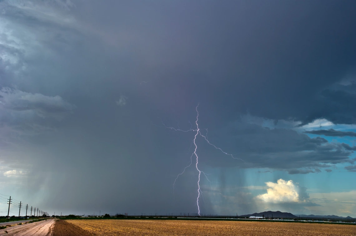 an agricultural landscape showing rain and a single lightning bolt