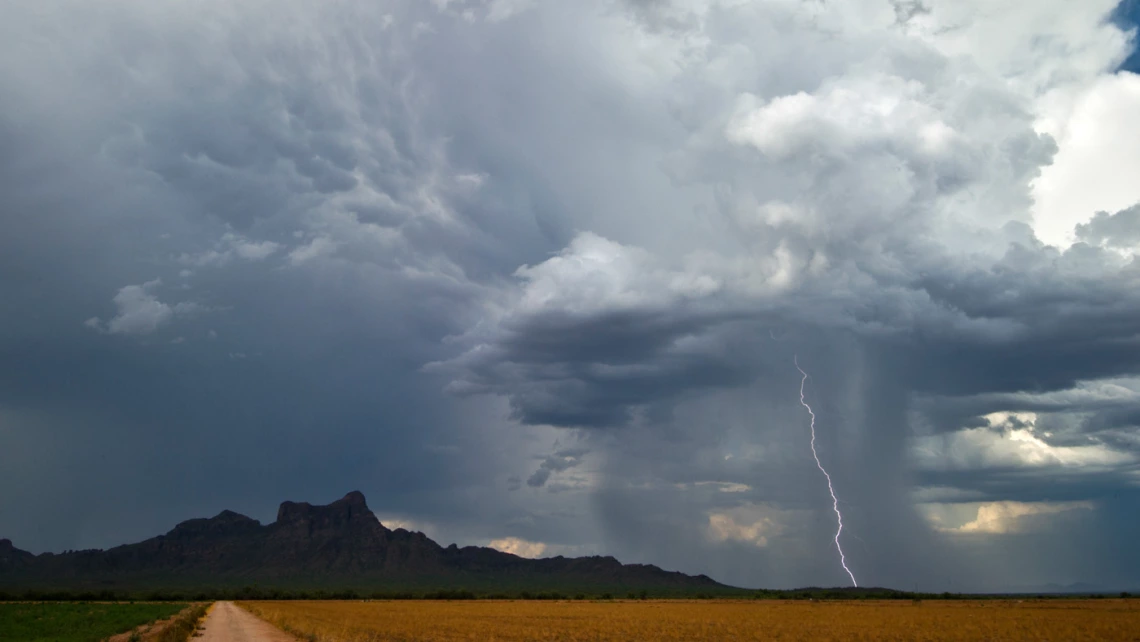 landscape showing rain and a single lightning bolt