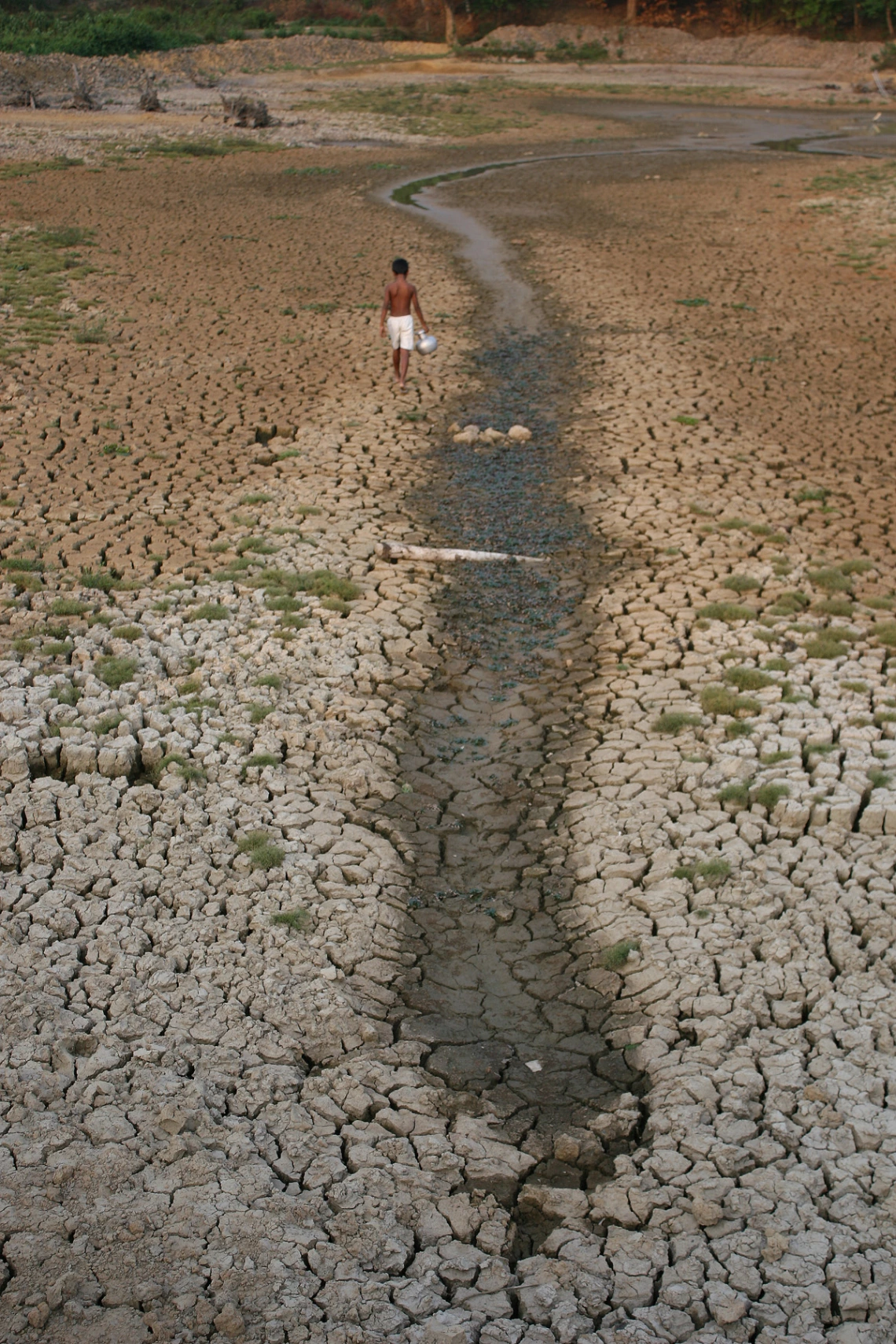 photo of a person walking next to a semi-dry stream