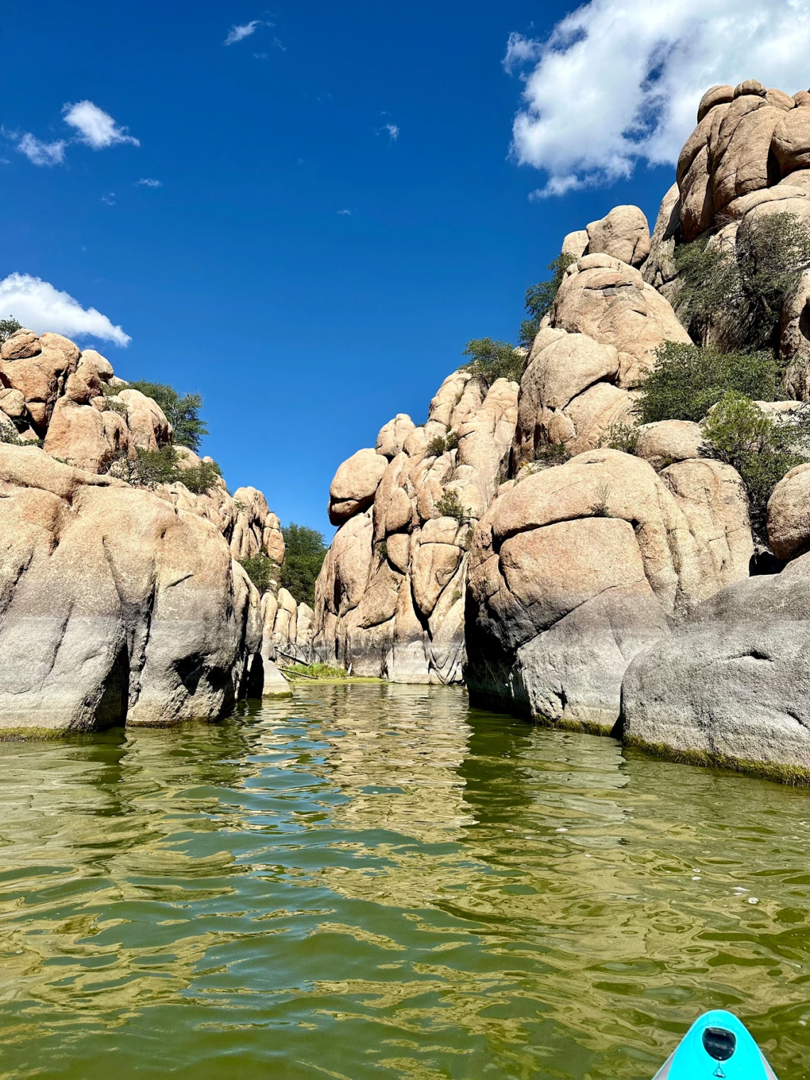 Paddleboarding Watson Lake - perspective of paddleboarder. rocky canyon walls, green water, and blue sky with few white clouds