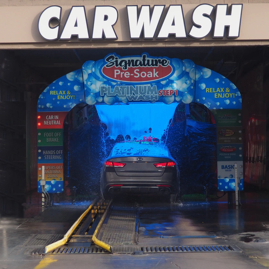 colorful photo a a car going through a carwash. Inside has a blue cast