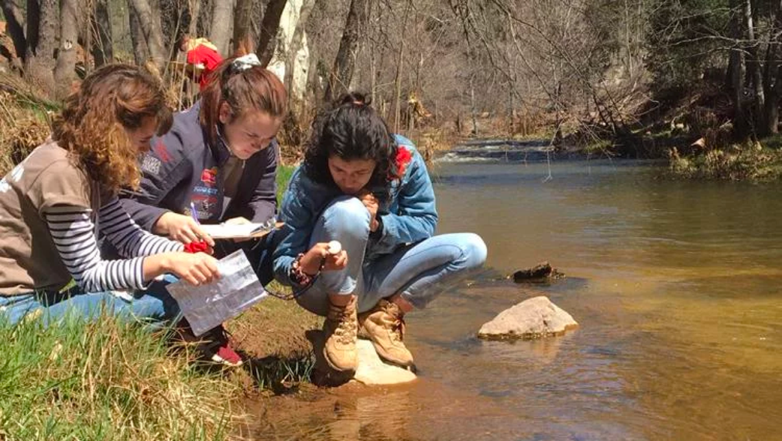 Student teams examining water by river